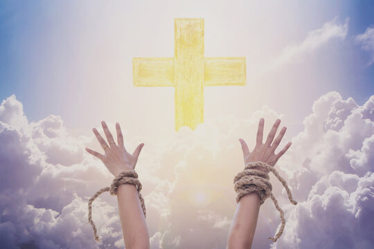 woman hands with broke rope raised up with light cross on the sky over the hug white cloud background, Christian praise and worship, Spiritual freedom conceptual image 