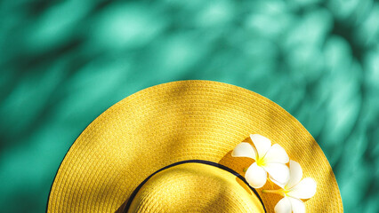 Yellow straw hat over green turquoise background with sunlight ,Minimal summer beach sea