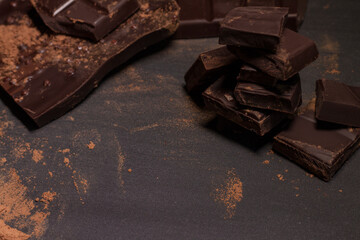 Broken slices of chocolate on black background