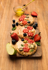Summer dessert sandwiches with peanut butter with fruits and berries with maple syrup on a wooden board, top view. Healthy tasty breakfast
