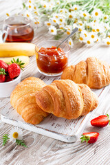 Fresh croissants with jam for breakfast on table. French pastry