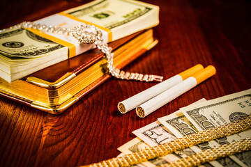 Money with a leather diary and cigarettes with jewellery on a mahogany table