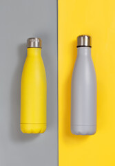 Grey and yellow insulated reusable bottles on grey and yellow background