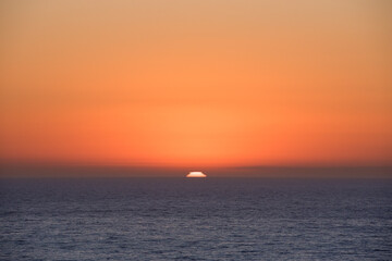 Sunset over the ocean horizon with bright orange sky