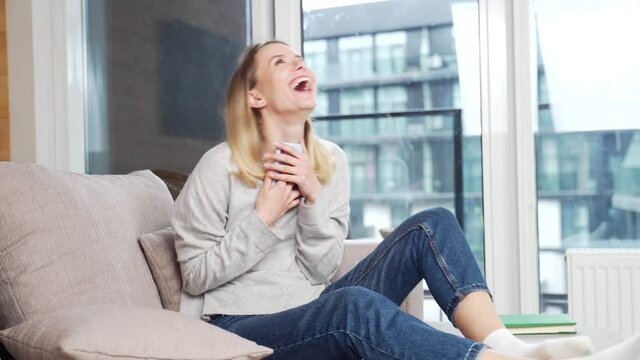 Portrait excited young woman winner screaming yes rejoicing success looking at cellphone. Happy overjoyed girl holding mobile phone celebrate good news surprise bid win app victory sit on sofa at home