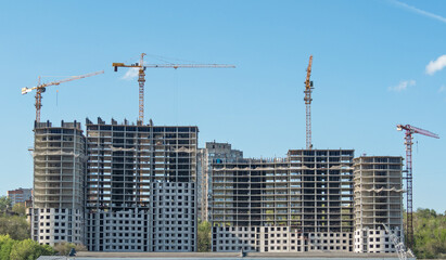 Construction project with building cranes. Unfinished residential house or skyscraper