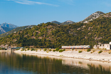 View at a dam with a train at railway Bar - Belgrade at Lake Skadar in Montenegro, National Park, famous tourist attraction and the largest lake in Southern Europe.