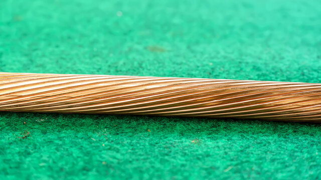 The copper strands of large wires on a artificial grass background.