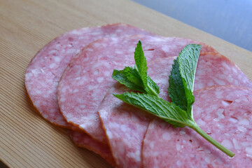 Salami with mint on a bamboo chopping board. 