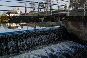 Alsunga catholic church and reflection in lake, Latvia. 