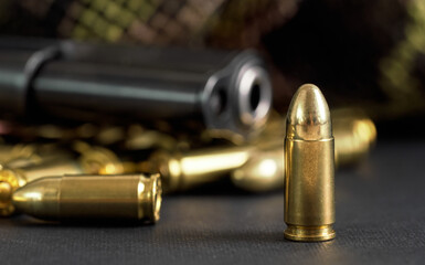 Single yellow brass bullet detail, black metal gun in background