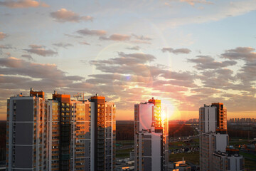 The sky at sunset from a tall building. Beautiful view of the modern city with high-rise buildings against the background of the sky and the sun.