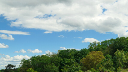 White clouds over a forest. Cumulonimbus in a blue sky over a hill at countryside.