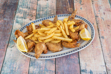 tray of fried wings and chips with lemon wedges