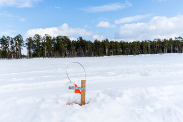 fishing rod on the ice in winter river sunny day, blue sky. Winter fishing. Copy space