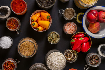 Top view image of dry seasoning jars with fresh fruits and vegetables in bowls