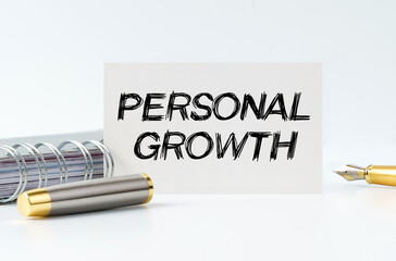 On the table is a notebook, a pen and a business card with the inscription - PERSONAL GROWTH