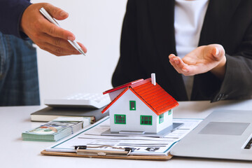 The businessman discusses the terms of the home purchase contract and asks the customer to sign a document to legally enter into the contract. Real estate ideas and home sales with home insurance