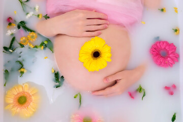Obraz na płótnie Canvas Yellow flower on the belly of a pregnant woman in a bath with water