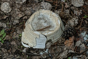 garbage of old dirty white  broken plastic bowl in dry gray leaves in nature