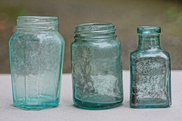 three small old dirty glass bottles on a gray table