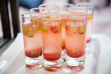 Rows of pink cocktail glasses with floating fruit