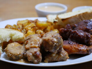 Alitas BBQ servidos con papas y pan al ajo