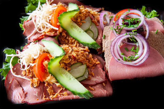 Smorrebrod a traditional Danish open sandwich that consists of a piece of dark rye bread, topped with cold cuts, pieces of meat or fish, cheese or spreads, and garnishes. Close up image.