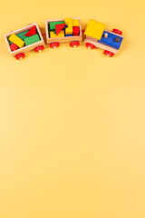 Wooden toy train on pastel yellow background. Top view