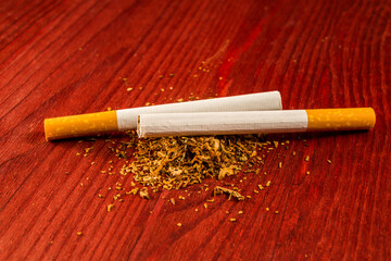 Two cigarettes on a fill of tobacco on the table. Close up view