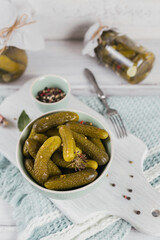 Marinated cucumbers gherkins with dill and garlic in glass jar on the white wooden table