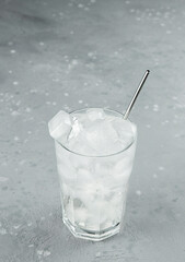 Glass with water and ice close-up on a gray background.