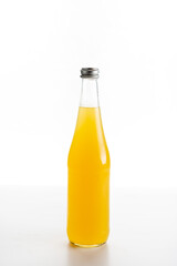 glass bottle of orange lemonade on a white background