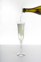 sparkling wine champagne from a bottle is poured into a glass glass flute on a white background