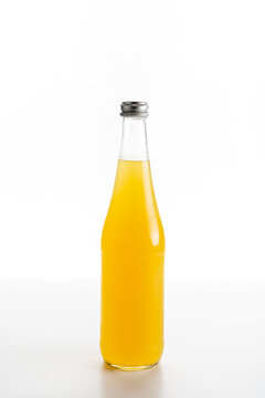 glass bottle of orange lemonade on a white background