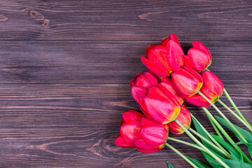 Red tulips on a brown wooden background. Mothers Day. March 8. Place for an inscription. The basis for the postcard.