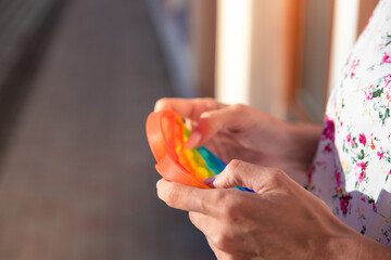 hands of a girl in a frame with a toy antistress pop it in the form of a heart on a background of a cityscape with a place for an inscription