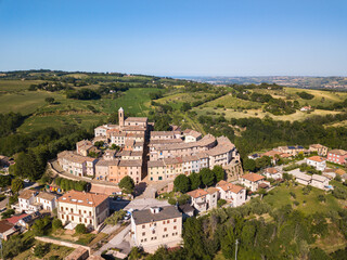 Naklejka premium Italy, May 2021. Aerial view of the medieval village of Serrungarina in the province of Pesaro and Urbino in the Marche region. You can also see the green hills around.