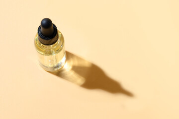Cosmetics primer oil or essence in glass bottle on beige background. Close up. Copy space.