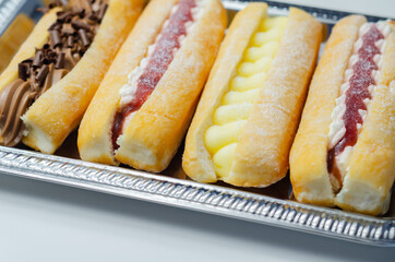 Mixed finger donuts filling chocolate, custard, jam and whipped cream, eclairs in different flavors
