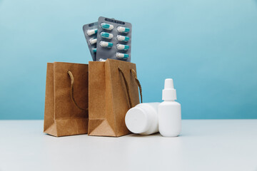 Bags with medical white containers and pills on blue background, online shopping theme