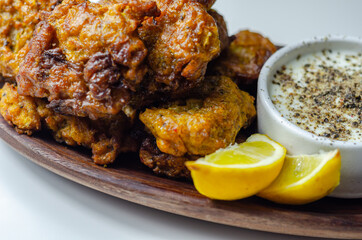 Delicious onion bhaji fritters served on wooden plate with white dip