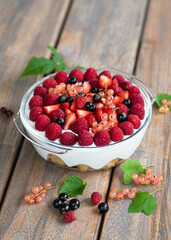 Homemade raspberry, strawberries, black and rosa currants dessert, cheesecake, trifle, mouse in a glass on a wooden table in the garden. Sweet food concept. 