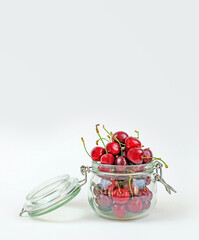 Fresh cherry in a jar on white background, harvesting for winter, copy space, vertical photo