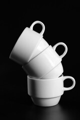 Stack of white coffee cups on black background close up