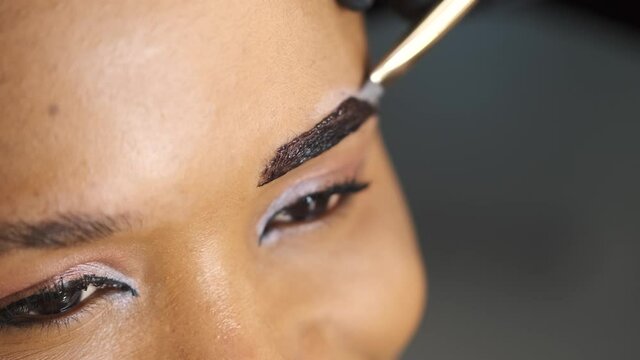 Master in black gloves makes permanent eyebrow makeup