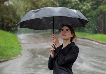 Attractive brunette under an umbrella catches raindrops.