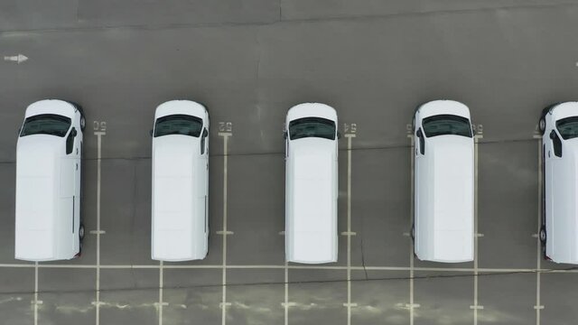 Minibuses (station wagon or shortbus) stand on the dealership cars export or customs terminal.  Aerial top down view of a rows of a new commercial vehicles