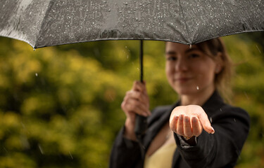 Attractive brunette under an umbrella catches raindrops.