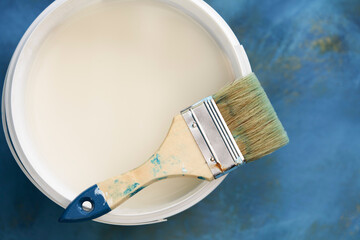  Top view of a bucket with white paint on a blue background. Selective focus.